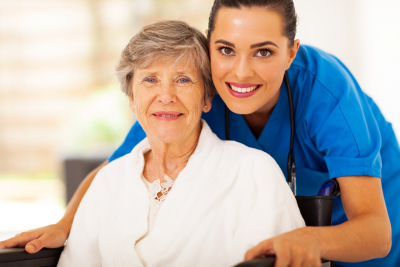 senior woman on wheelchair with nurse wearing stethoscope smiling