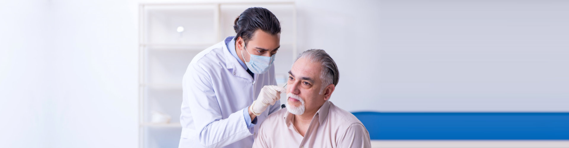 caregiver checking elder man's ear